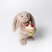Load image into Gallery viewer, Jellycat Bashful Beige Bunny | Birthday Plush bunny holding a cupcake with a candle on a white background