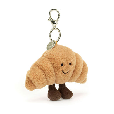 Jellycat Amuseables Croissant Bag Charm Plush croissant-shaped keychain with a smiling face on a white background